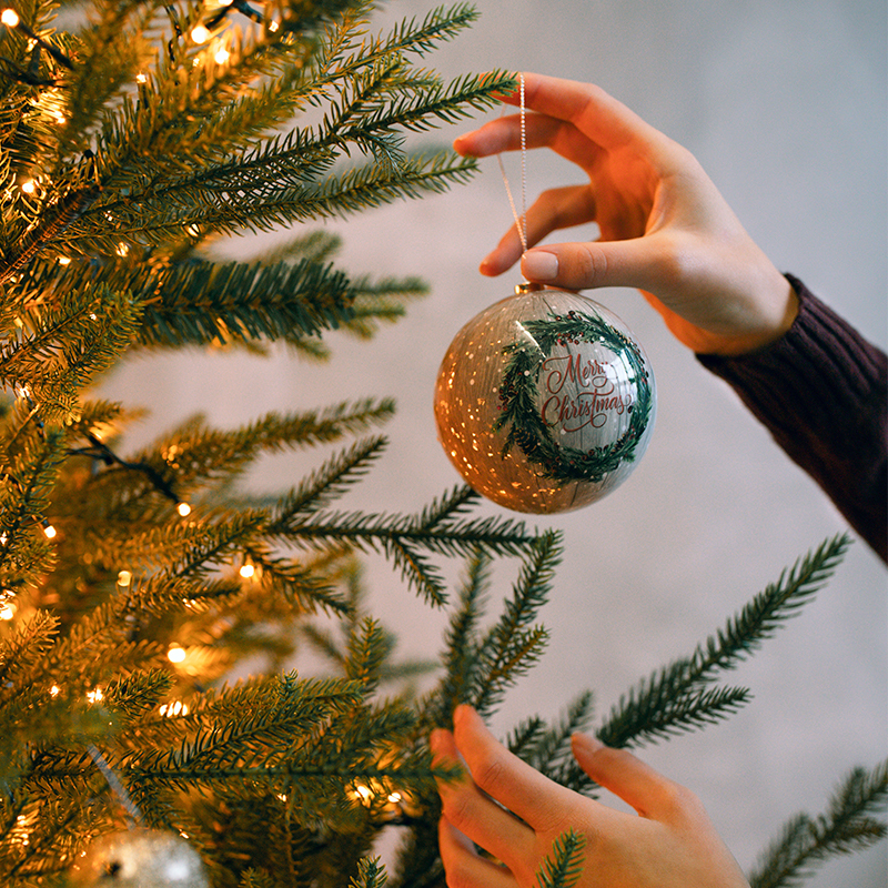 Benefits of custom ornaments A person is decorating the Christmas tree with Christmas balls