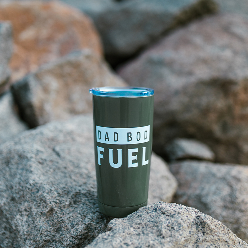 Design Your Own Tumbler Cup A green thermos mug with text is placed on a stone