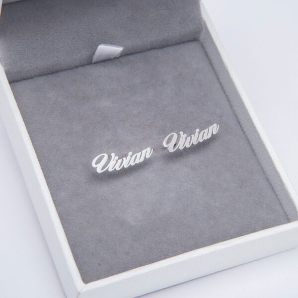 A pair of silver earrings are placed in a jewelry box