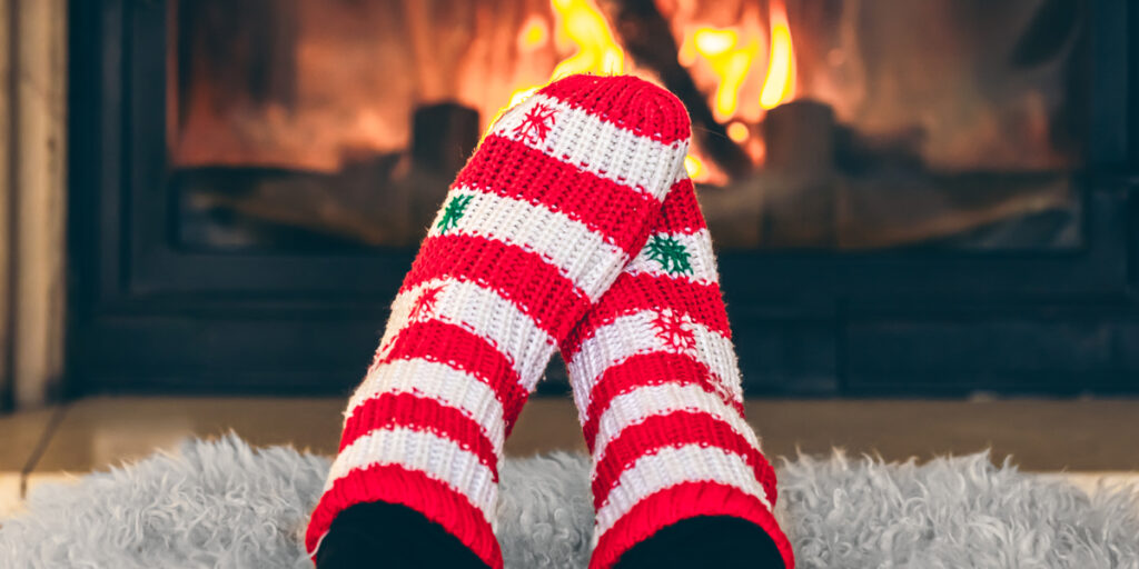 A person wearing a pair of warm socks in front of a fireplace